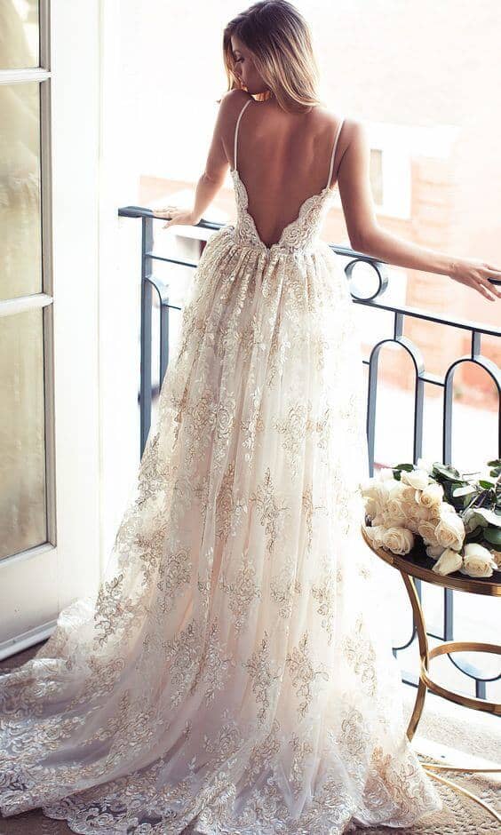 47 perfect bridal gown ideas - find yours 13 Backless lace bridal gown in champagne-ivory, standing on a wrought-iron balcony. Sunlight highlights the intricate lace and flowing train.