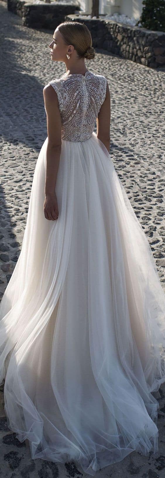47 perfect bridal gown ideas - find yours 14 Back view of a bride in an ivory tulle a-line gown with a beaded illusion bodice, walking a sunlit mediterranean cobblestone street.