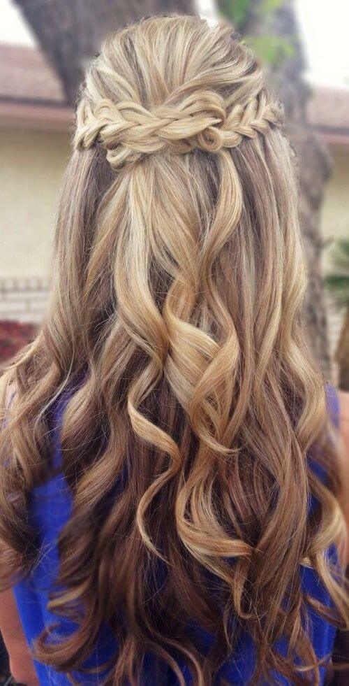 39 popular wedding hairstyles for brides to make your big day perfect 23 Romantic half-up braided crown with beachy waves, showcasing honey-blonde hair against a blurred outdoor backdrop. Perfect for weddings.
