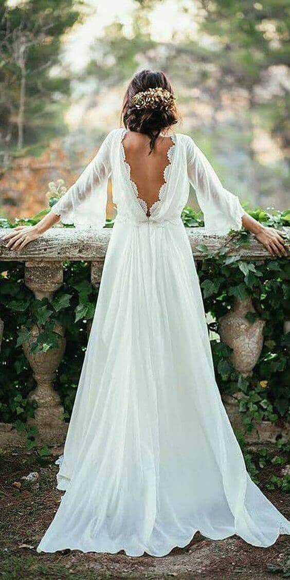 47 perfect bridal gown ideas - find yours 32 Bridal portrait featuring a bride in a flowing ivory gown with a lace v-back, set in a lush garden terrace surrounded by greenery.
