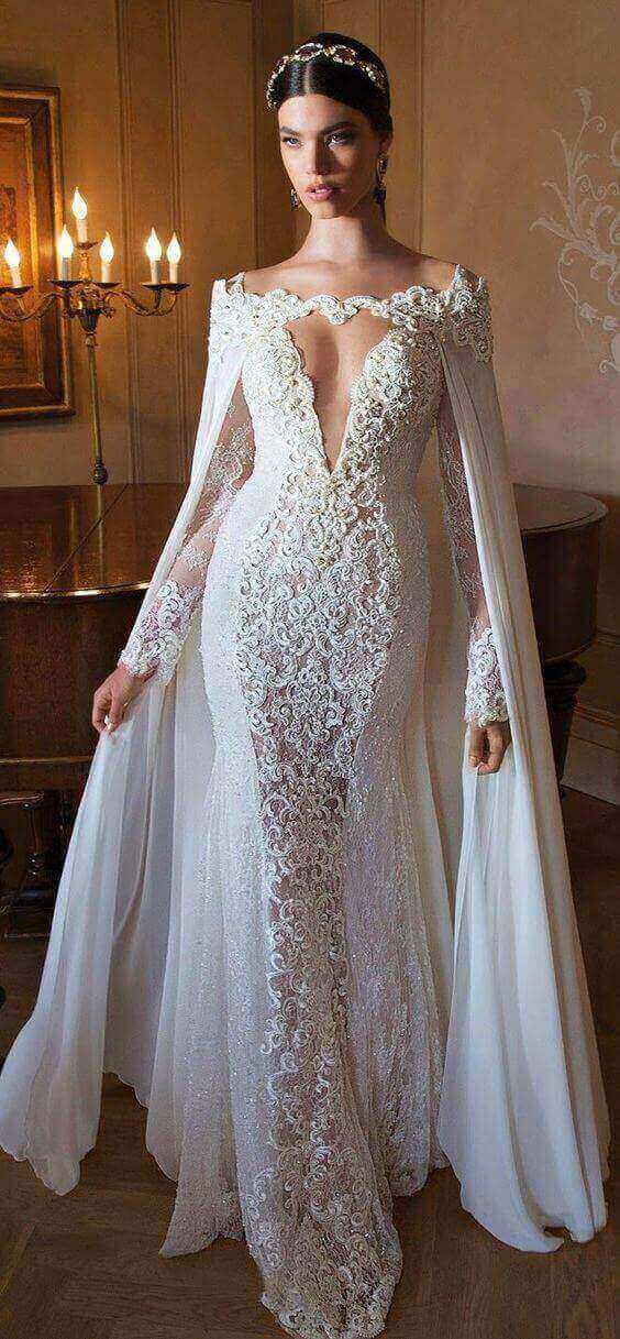 47 perfect bridal gown ideas - find yours 37 Bride in a diamond-white lace fit-and-flare wedding gown with off-the-shoulder neckline and chiffon cape, set in a candlelit vintage salon.
