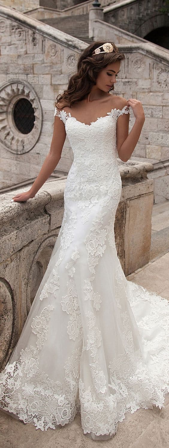 47 perfect bridal gown ideas - find yours 6 Bride in an ivory lace fit-and-flare gown with an off-the-shoulder neckline, posing on a historic stone staircase.