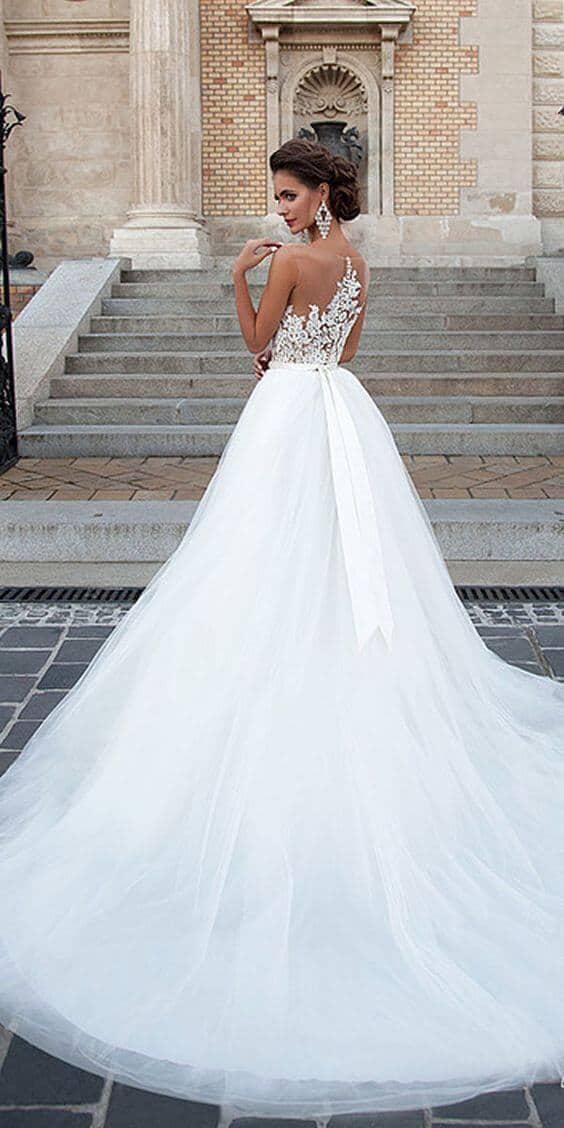 47 perfect bridal gown ideas - find yours 42 Bridal gown featuring a lace-illusion back and long tulle train, posed on historic stone steps of a classical building.