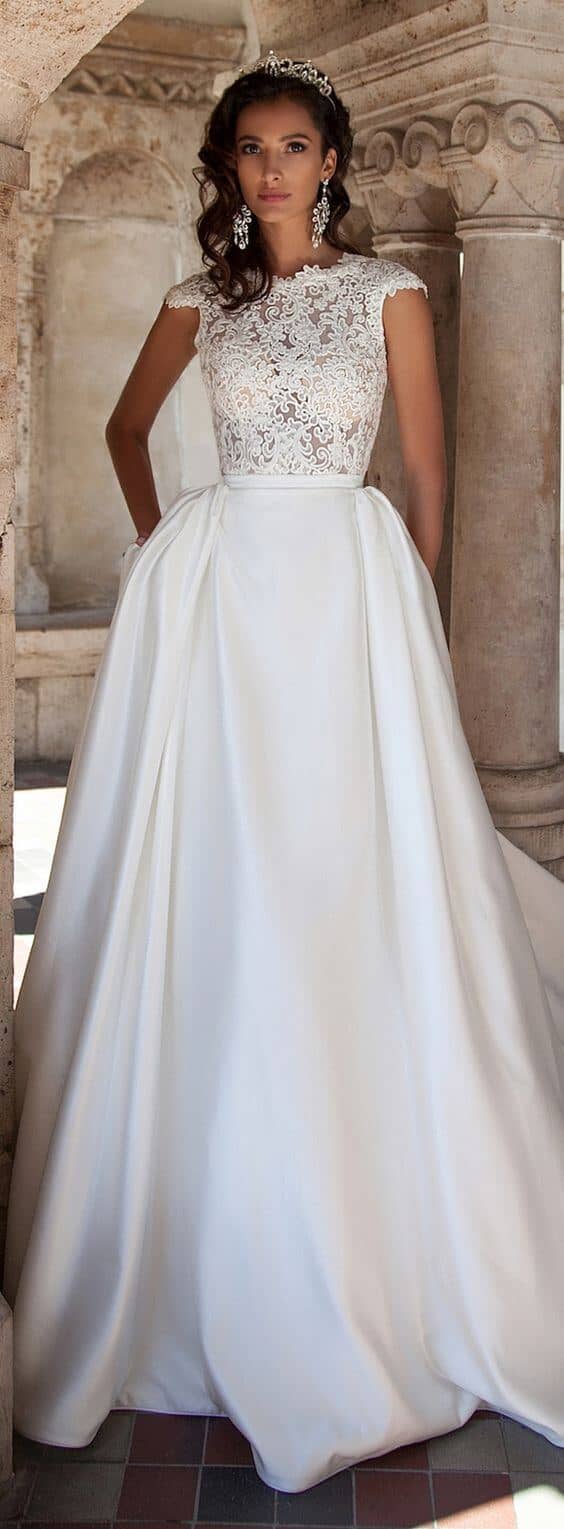 47 perfect bridal gown ideas - find yours 45 A bride in a classic bridal gown with a lace bodice and satin ballgown skirt stands gracefully in a historic colonnade, exuding timeless elegance.