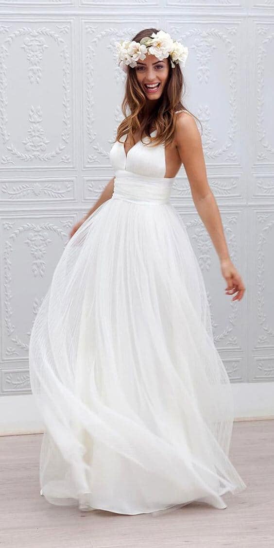 47 perfect bridal gown ideas - find yours 9 Bride twirling in a white a-line tulle wedding dress with a deep v-neck and ivory floral crown, set against a light-gray studio backdrop.