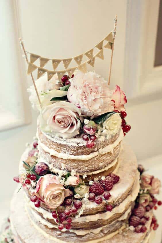 41 best wedding cake designs ideas for your big day 20 Three-tier semi-naked wedding cake with blush roses, peonies, and cascading berries. Soft natural light enhances its rustic elegance.