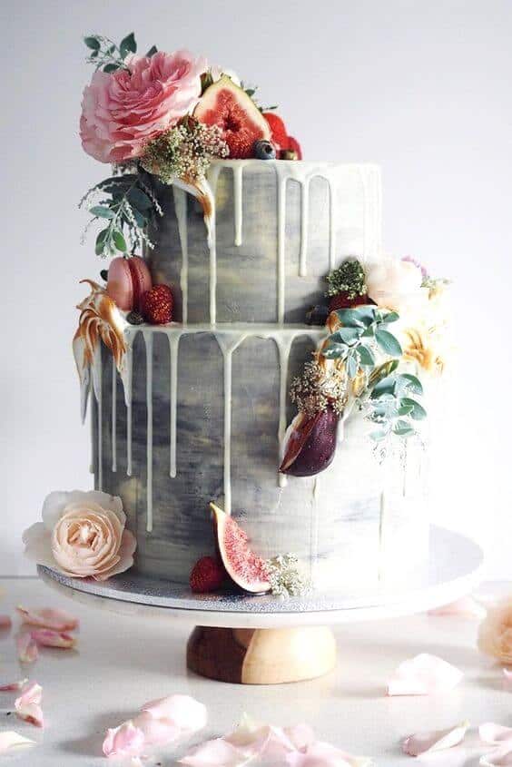 41 best wedding cake designs ideas for your big day 27 Two-tier wedding cake with grey marble buttercream and white-chocolate drip, adorned with figs, berries, and florals on a wood pedestal.