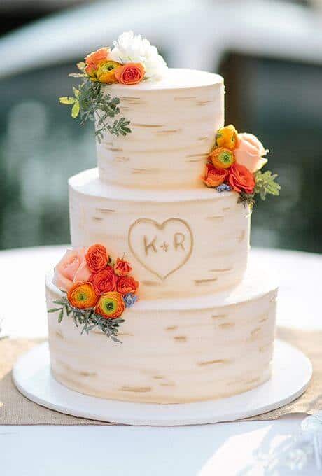 41 best wedding cake designs ideas for your big day 30 Three-tier wedding cake with a birch-bark effect, adorned with peach roses, ranunculus, and a carved heart monogram "k + r".
