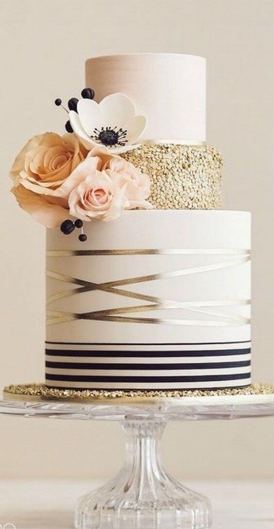 41 best wedding cake designs ideas for your big day 31 Three-tier wedding cake on a glass pedestal. Ivory base with black stripes, gold sequined middle, and smooth blush top tier, adorned with blush roses and anemone.