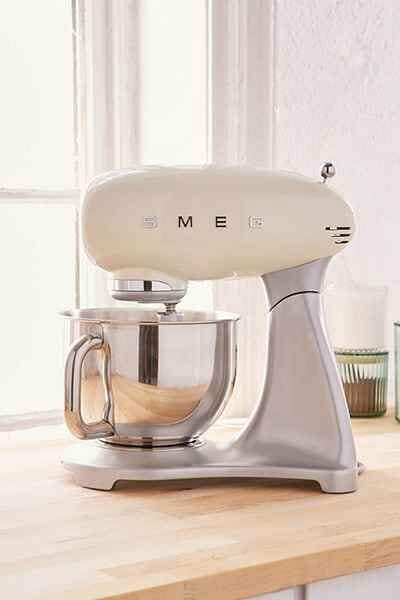 20 clever bridal shower gift ideas to be innovative 15 Cream smeg stand mixer with a stainless-steel bowl on a light wood countertop, illuminated by soft daylight from a nearby window.