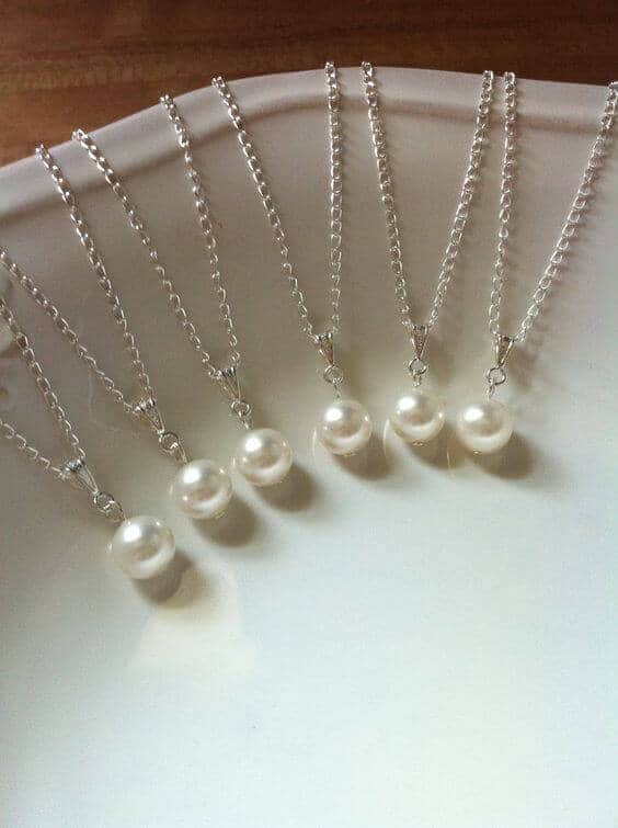 38 wedding accessories list - ideas to transform your big day into magic 16 Set of silver-chain pearl pendant necklaces elegantly fanned on a white dish, perfect wedding accessories for bridesmaids.