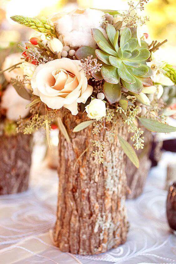 31 autumn wedding flowers ensembles perfect for your special day 19 Rustic wedding centerpiece with a hollow wood log vase filled with blush roses, succulents, and greenery on a reception table.