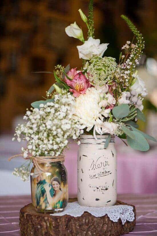 34 budget wedding ideas for a creative affordable wedding 27 Rustic mason jar centerpiece on a wood slice, featuring a wildflower bouquet and lace doily, perfect for budget-friendly weddings.