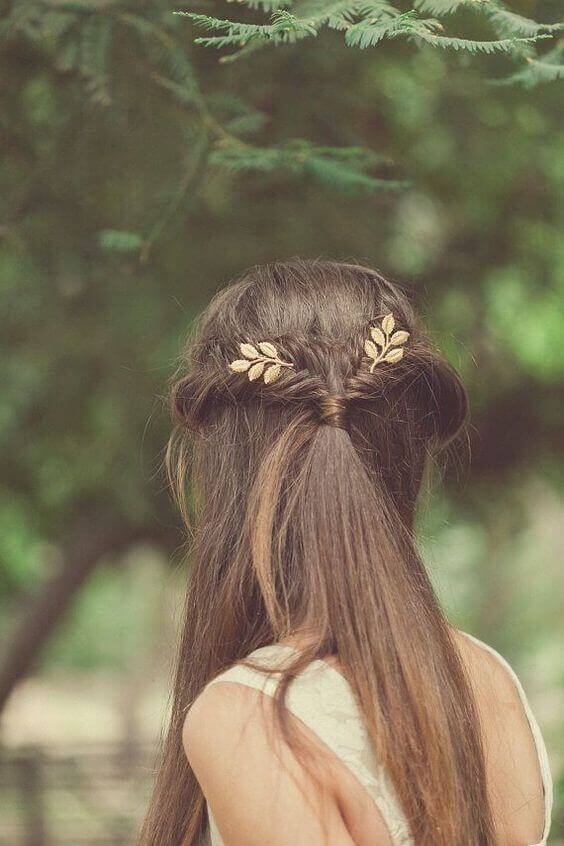38 wedding accessories list - ideas to transform your big day into magic 27 Bridal hairstyle featuring a half-up twist adorned with gold leaf hairpins, set against a soft, green woodland backdrop.