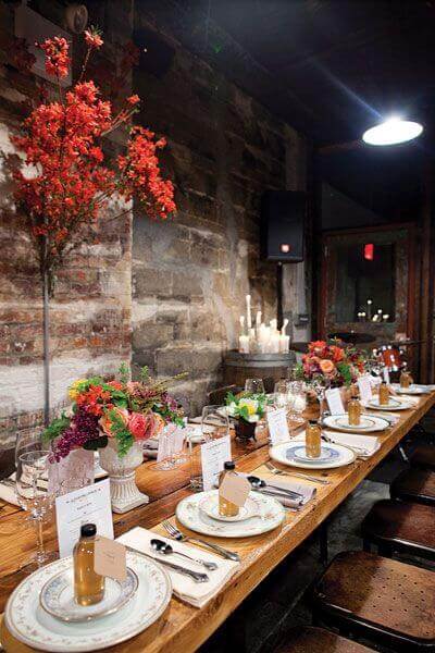34 budget wedding ideas for a creative affordable wedding 34 Candlelit rustic-industrial reception table set for an intimate wedding dinner, featuring vintage china, warm florals, and glowing candles.