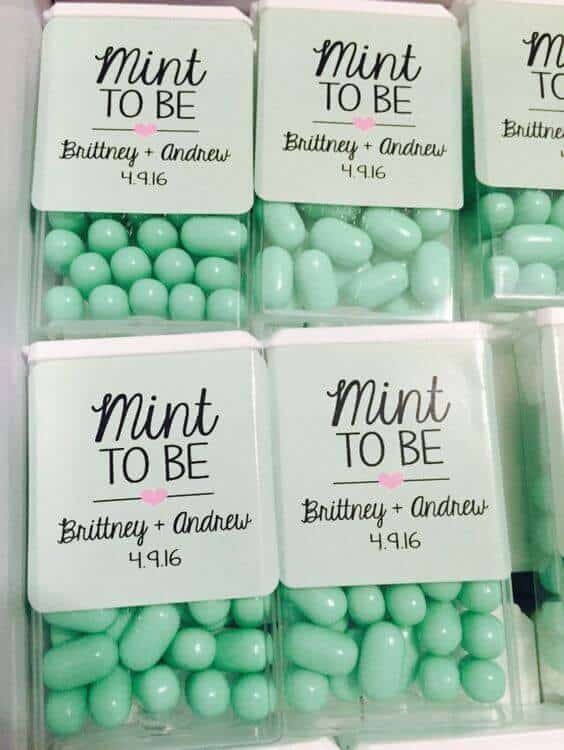 38 wedding accessories list - ideas to transform your big day into magic 34 Close-up view of mint-green candy boxes labeled 'mint to be' with a pink heart, featuring a couple's names and wedding date.