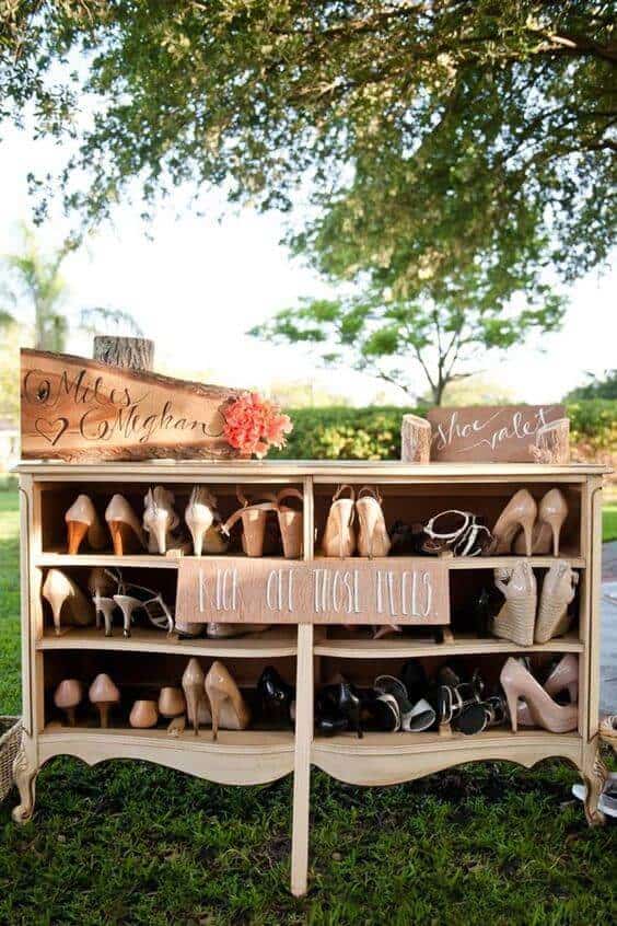 34 budget wedding ideas for a creative affordable wedding 11 Rustic shoe valet on a vintage dresser in a sunlit garden, featuring hand-lettered signs and neatly arranged heels, perfect for budget weddings.