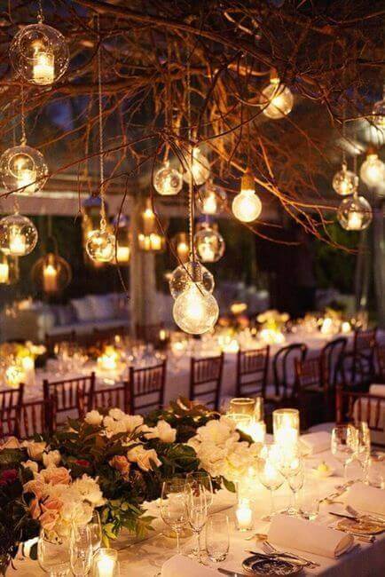 Twilight wedding reception under a clear marquee, featuring glass orbs with tea lights, candlelit tables, and lush floral centerpieces.