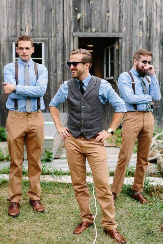 31 amazing wedding groomsmen suits suggestions 17 A trio of groomsmen in rustic-chic attire poses outside a weathered barn, wearing chambray shirts, tan chinos, and brown oxfords.