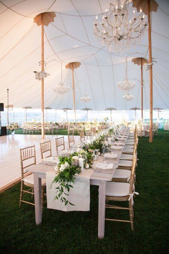 37 Morning Wedding Ideas filled with Sunshine color pallets 30 Elegant sailcloth tent wedding reception featuring a long greenery-draped banquet table, gold Chiavari chairs, and soft chandelier light.