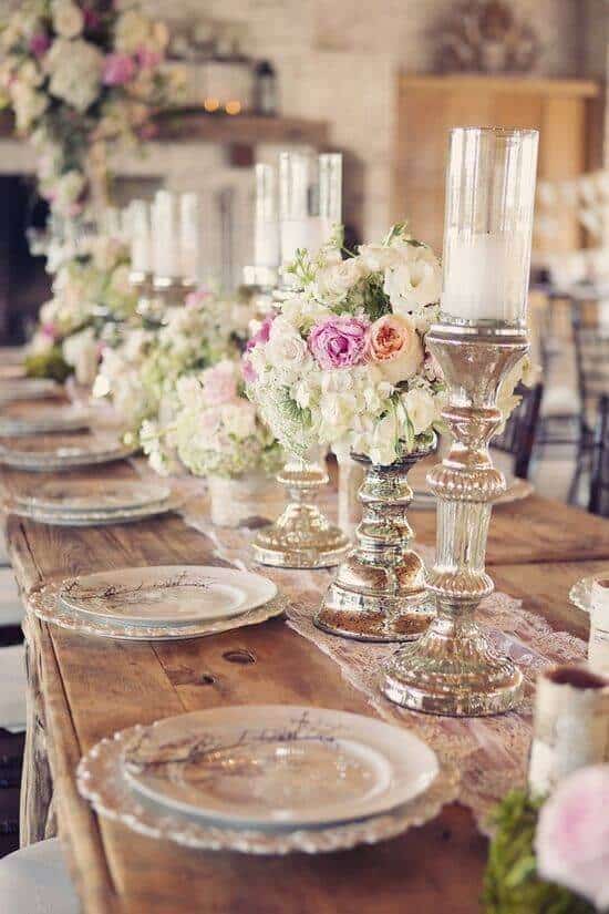 Rustic-glam wedding reception table with blush and ivory florals, mercury-glass candlelight, and a lace runner, set for an intimate dinner.