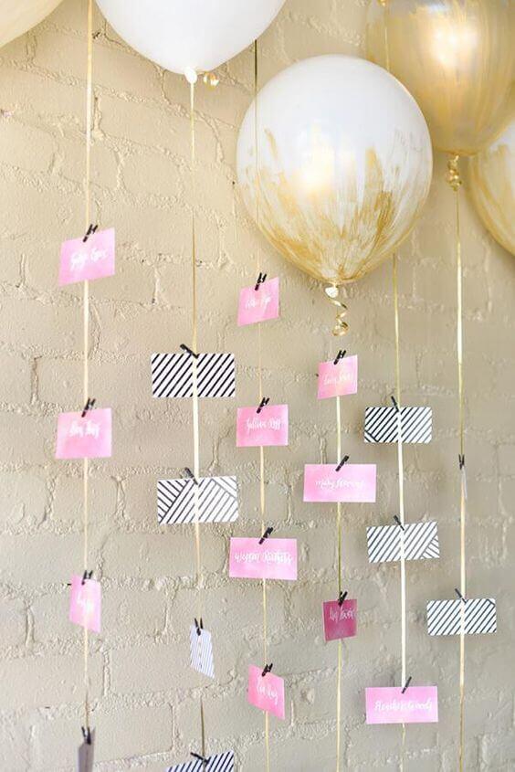 Blush-and-gold balloon escort card display featuring oversized helium balloons, satin ribbons, and alternating pink and striped escort cards.