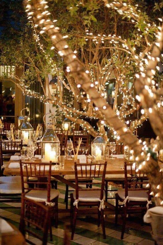 Intimate outdoor night wedding reception with twinkle-lit trees, candlelit tables, and rustic-elegant decor under a starry sky.