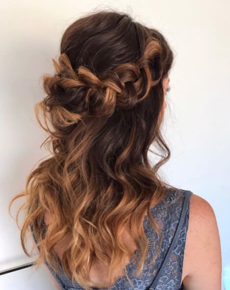 Half-up braided crown with loose balayage waves, viewed from the back, paired with a slate-blue lace dress. Perfect for a romantic wedding.