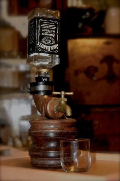 DIY whiskey dispenser featuring an inverted Jack Daniel's bottle and brass spigot, perfect for groomsmen gift ideas at a rustic wedding.